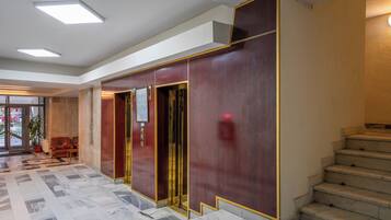 A lobby with a marble floor, a staircase, and a reception area with a desk and chairs.