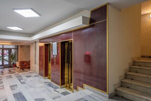 A lobby with a marble floor, a staircase, and a reception area with a desk and chairs. - Sarmis (Deva)