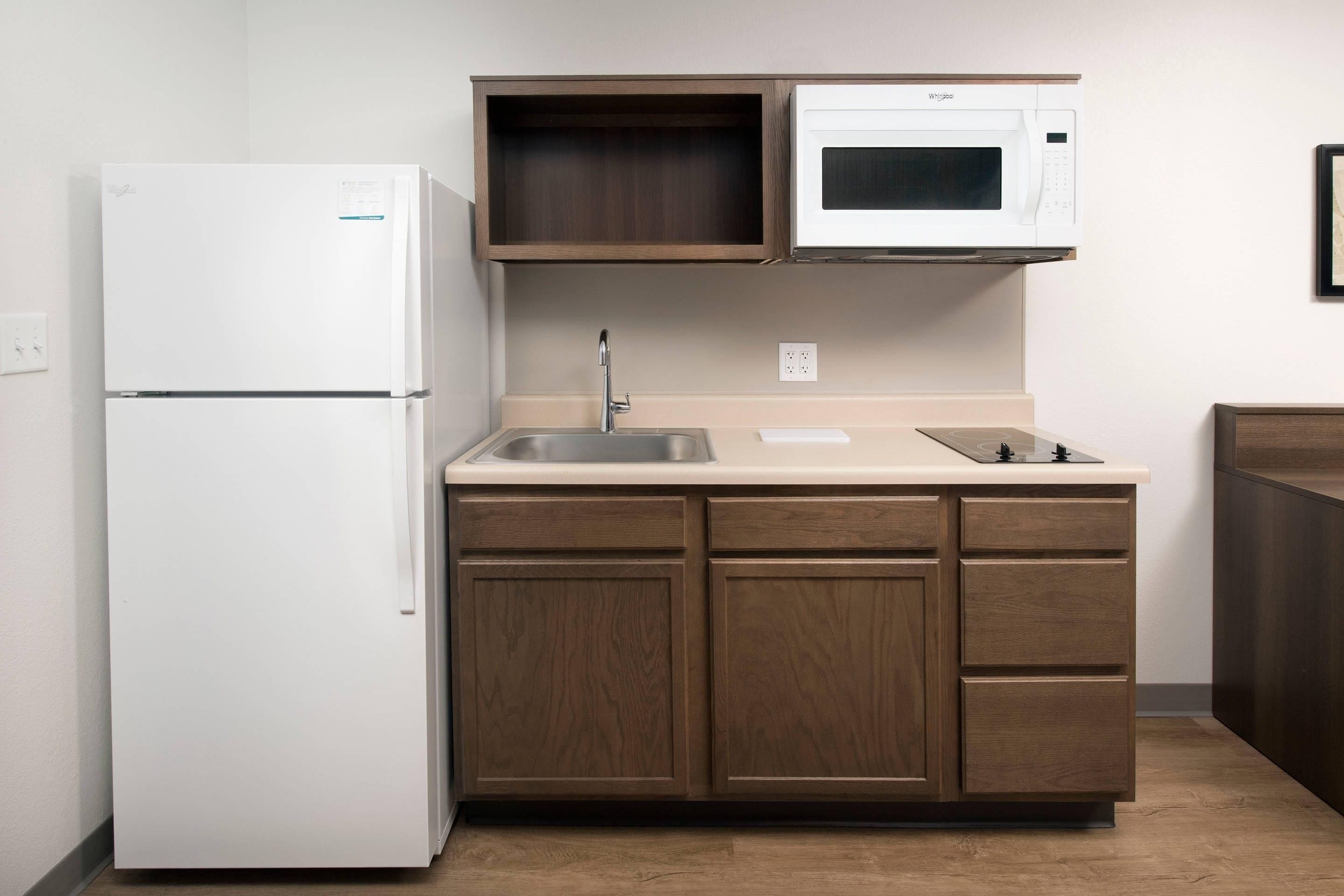 A compact kitchen with a white refrigerator, a microwave, and wooden cabinets.