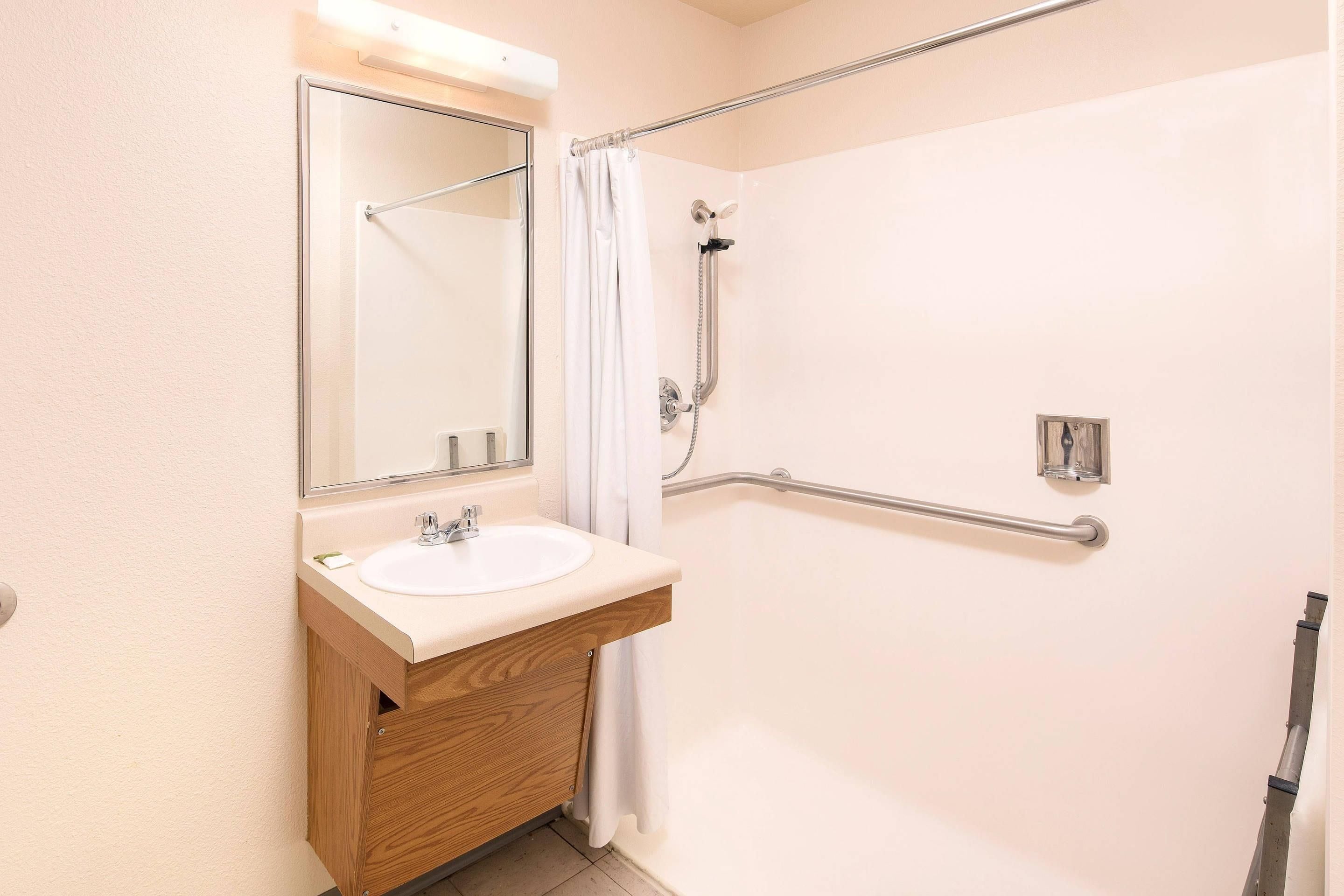 A bathroom with a white sink, mirror, and shower area.