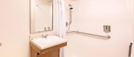 A bathroom with a white sink, mirror, and shower area.