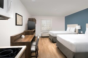 A hotel room with a kitchenette, a bed, a desk, and a TV. - WoodSpring Suites Charlotte Gastonia (Gastonia)