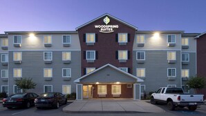 A hotel with a brick facade, multiple windows, and a sign reading "Woodspring Suites". - WoodSpring Suites Charlotte Gastonia (Gastonia)