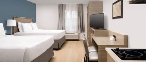 A hotel room with two beds, a desk, a television, and a window with curtains.