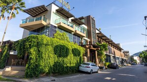 A modern hotel with a prominent 'NAVINDA' sign, a covered outdoor seating area, and a white car parked in front. - Navinda Krabi (Krabi)