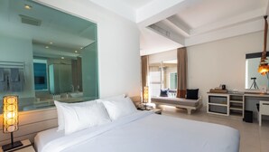 A modern hotel room with a large bed, a desk, a mirror, and a view of the city. - Navinda Krabi (Krabi)