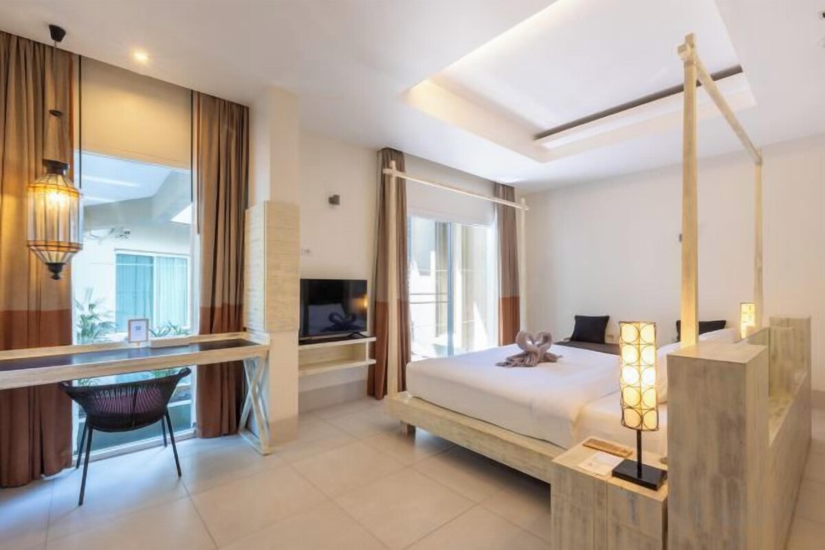 A modern hotel room with a bed, desk, and TV.