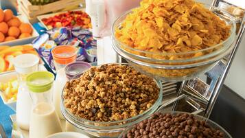 Buffet com diversas opções de alimentos, incluindo cereais, granola e bolinhas de chocolate.