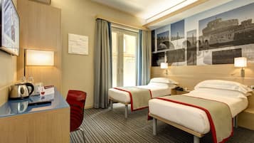 A hotel room with two beds, a desk with a kettle, a chair, and a large wall mural.
