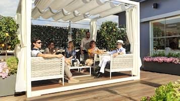 Un espacio de estar al aire libre cubierto con mobiliario de mimbre y un toldo blanco.