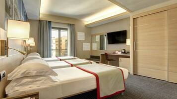A hotel room with two beds, a desk, a chair, a TV, and a wardrobe.