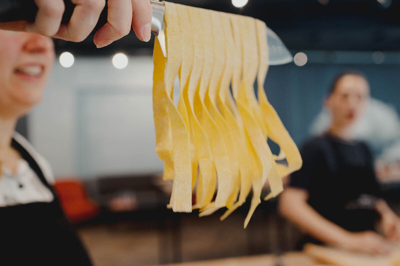 A person slicing yellow pasta.