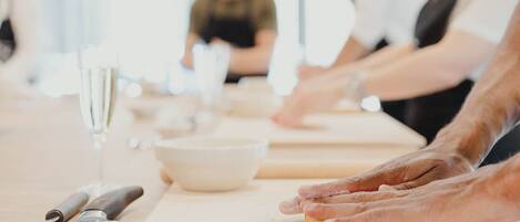 Un grupo de personas participa en una actividad de cocina, con un cuchillo, un bol y un rodillo sobre la mesa.