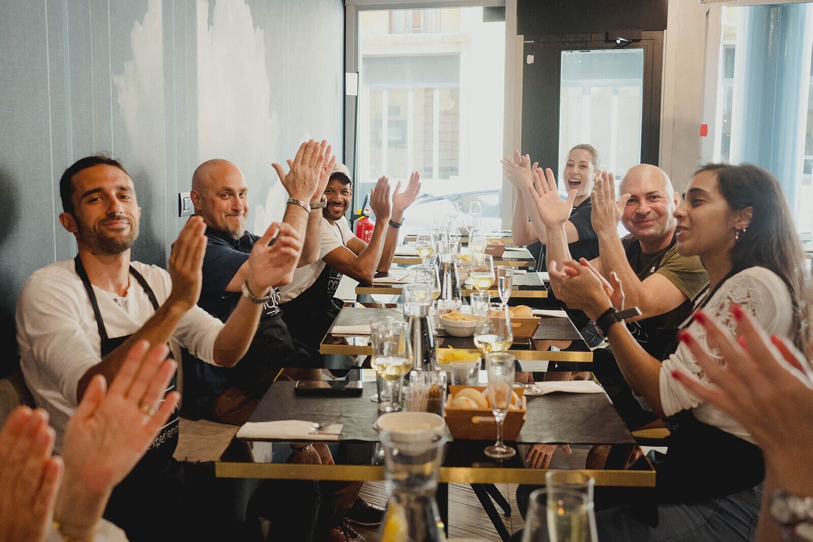 A group of people clapping around a table with food and drinks.