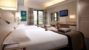 A hotel room with three beds, a television, a desk, and a window with curtains. - iQ Hotel Roma (Rome)