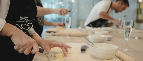 A kitchen scene with chefs preparing food, a rolling pin, a bowl, and a wine glass on the counter.