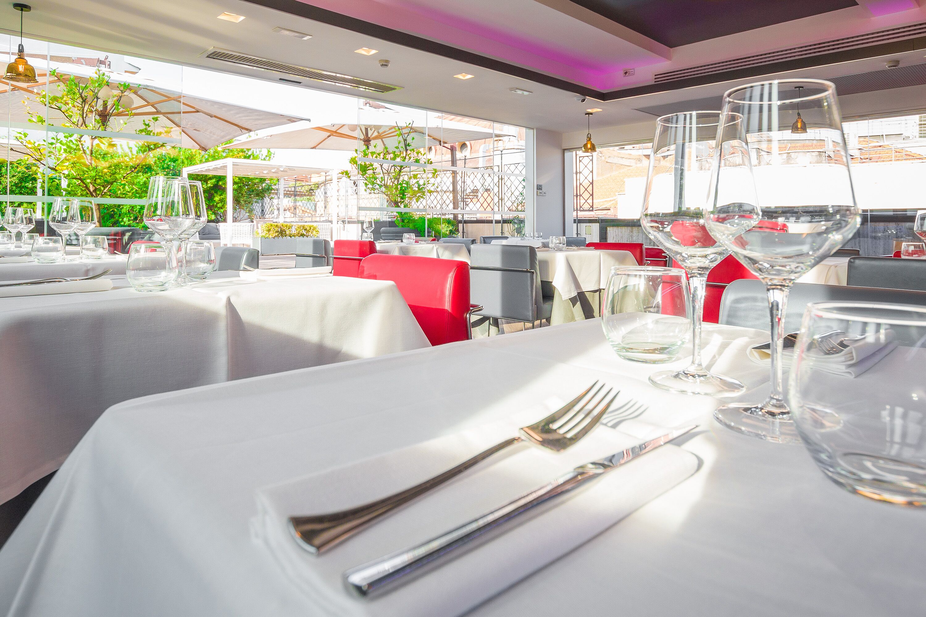 A restaurant with tables set for dining, featuring clear glassware and utensils.