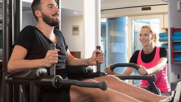 Une salle de sport équipée de matériel d’exercice, où une personne utilise un appareil de musculation pour les jambes.
