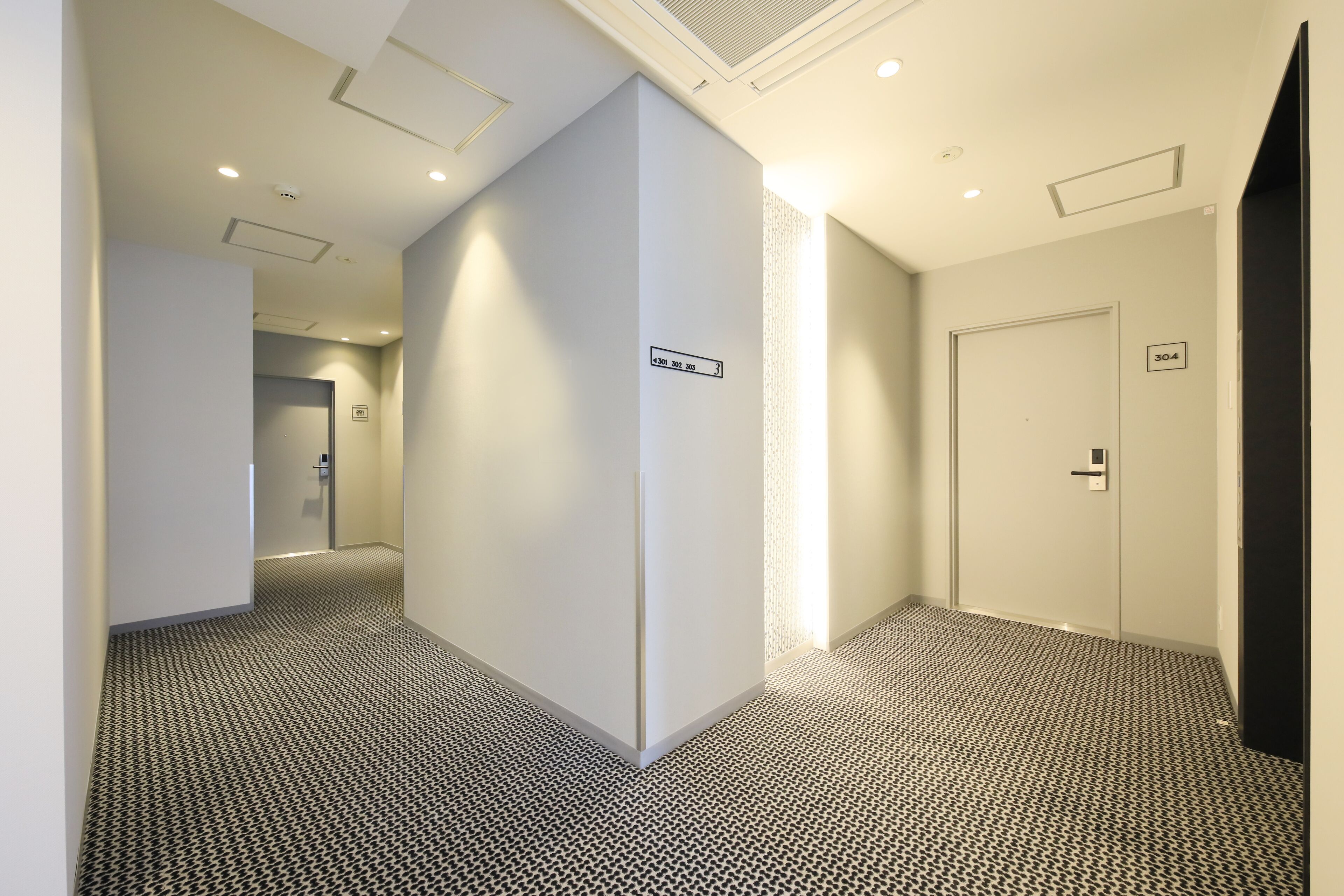 A hallway with a patterned carpet, white walls, and doors numbered 304 and 305.