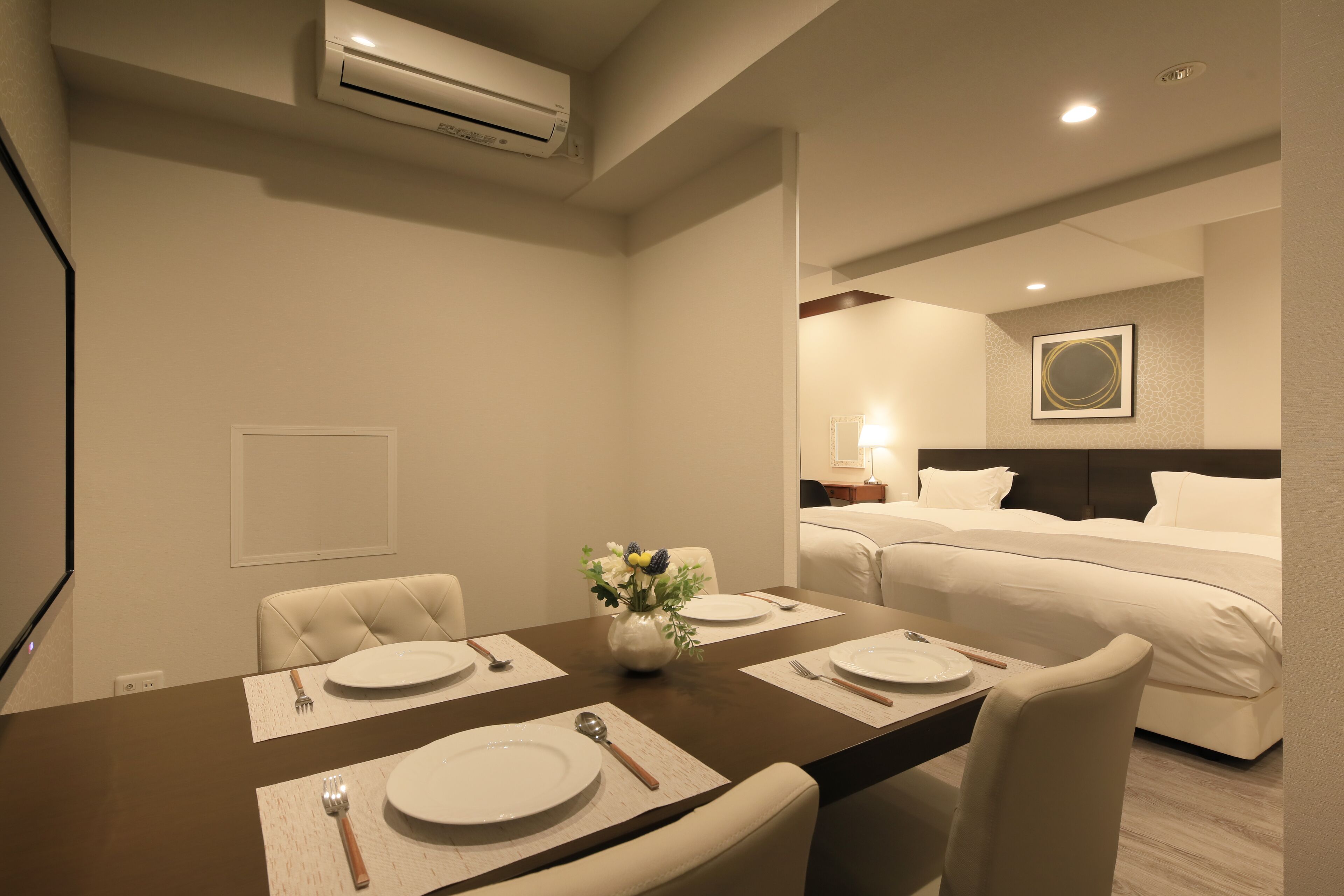 A hotel room with a dining area, a bed, and a bathroom.