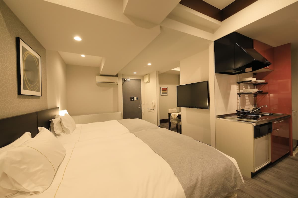 Une chambre d’hôtel comprenant un lit, une petite kitchenette, une télévision et une salle de bain.