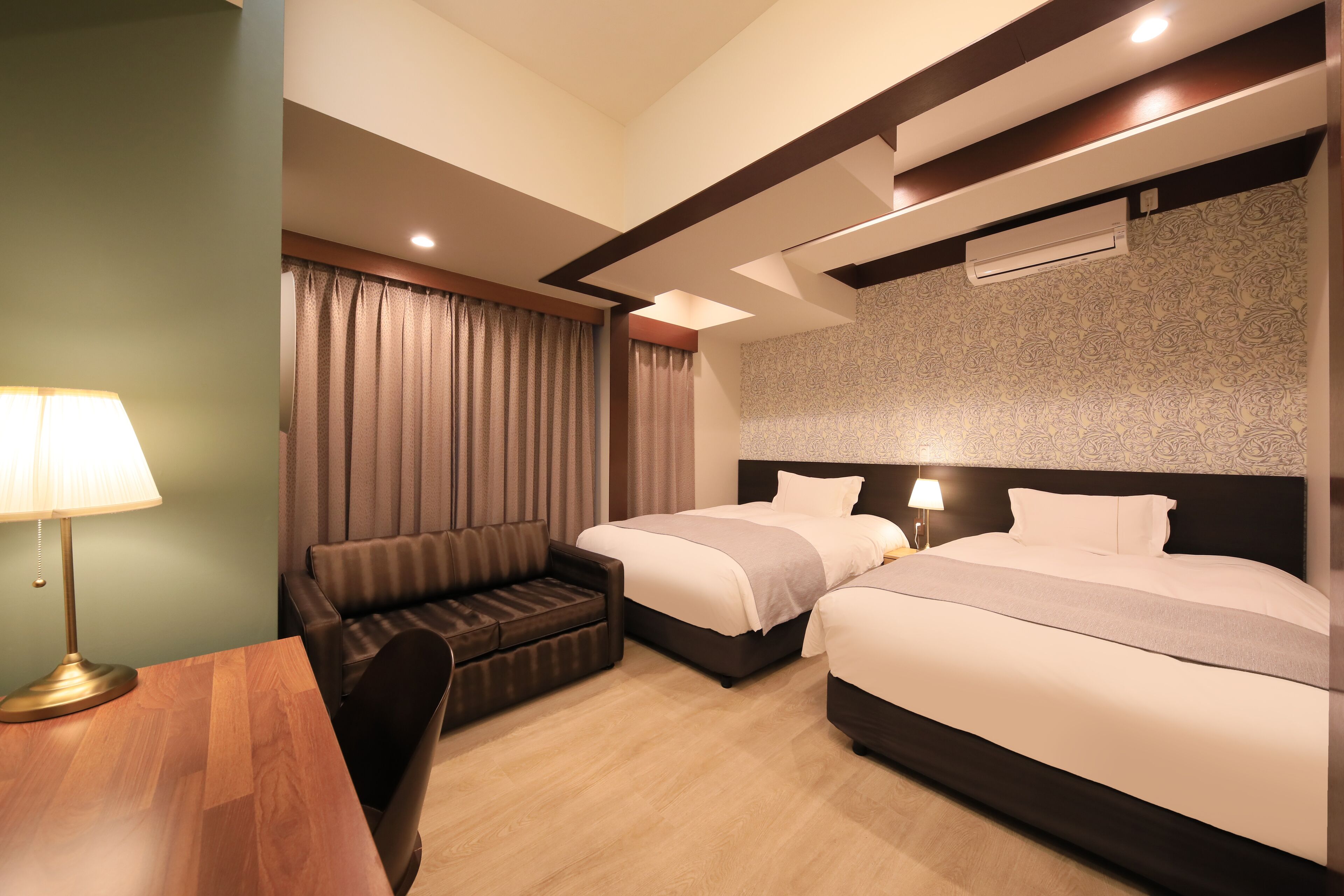 Habitación de hotel con dos camas, un sofá, un escritorio y una lámpara.