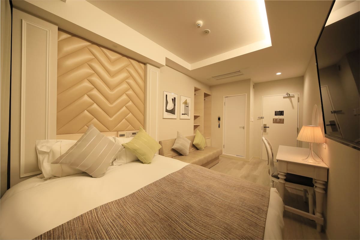 Une chambre d’hôtel moderne dotée d’un grand lit, d’un bureau et d’un espace douche.
