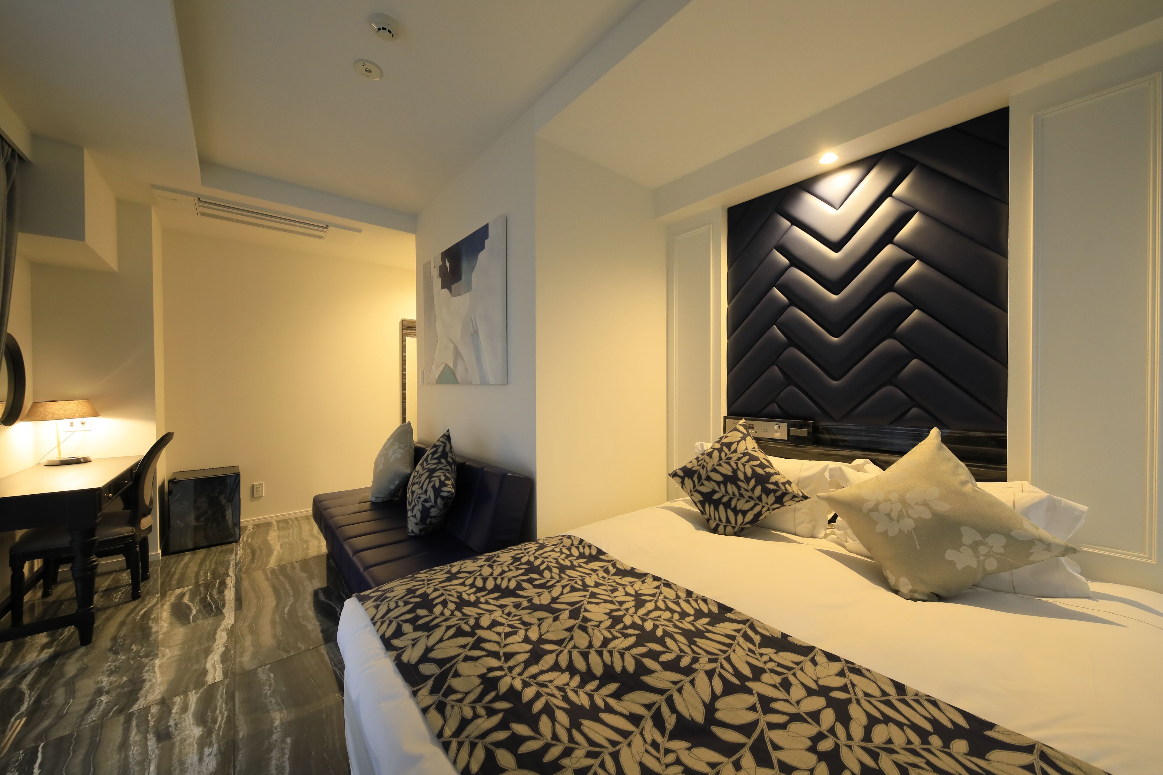 Ein modernes Hotelzimmer mit einem großen Bett, einem Schreibtisch und einem Stuhl.