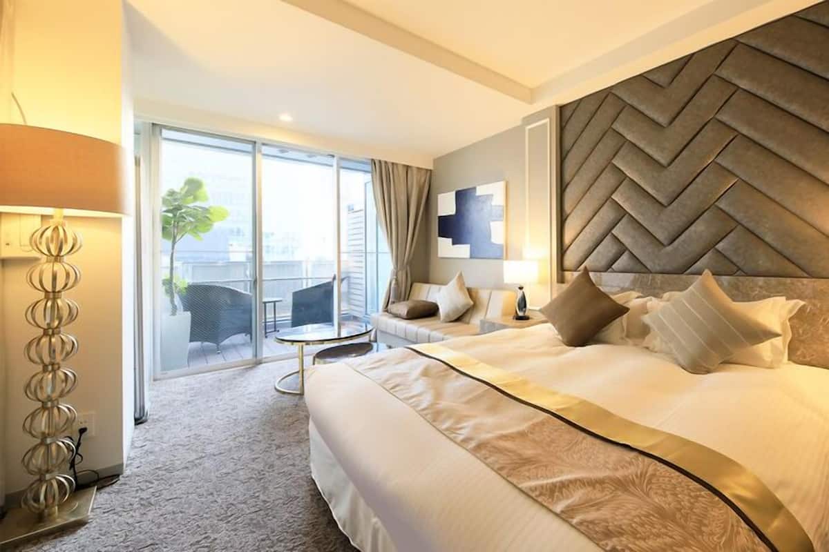 Une chambre d’hôtel avec un grand lit, un coin salon avec une table et une vue à travers une porte vitrée.
