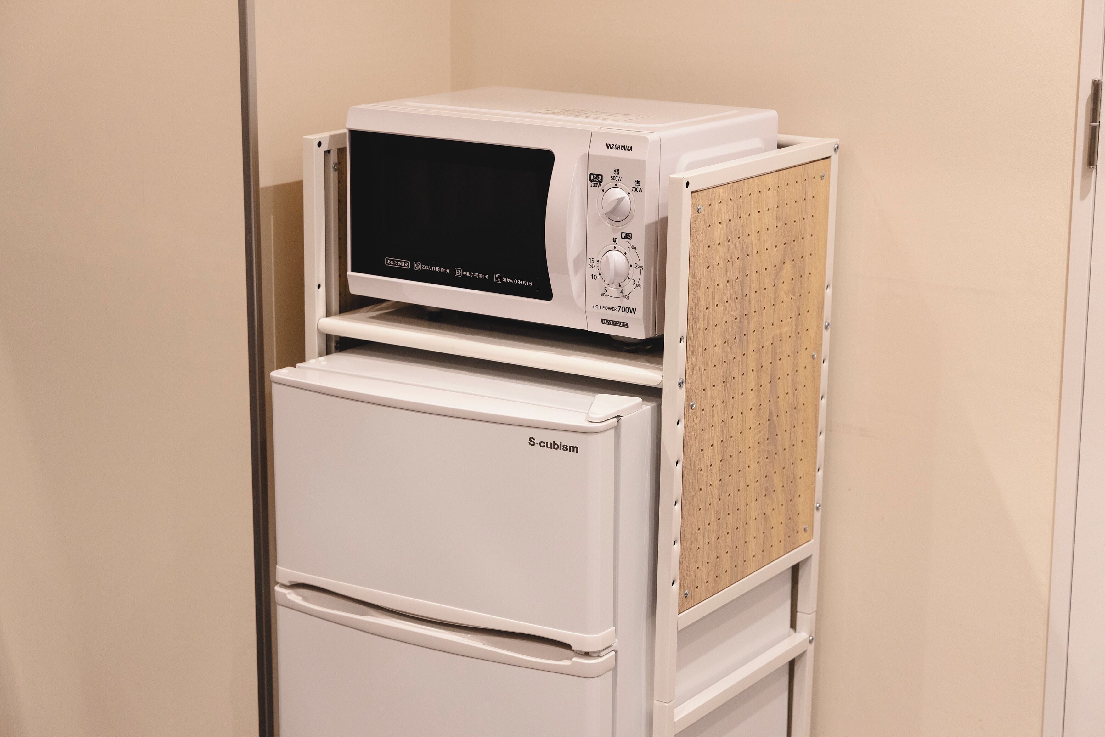 Un refrigerador blanco de estilo cubista con un microondas encima.