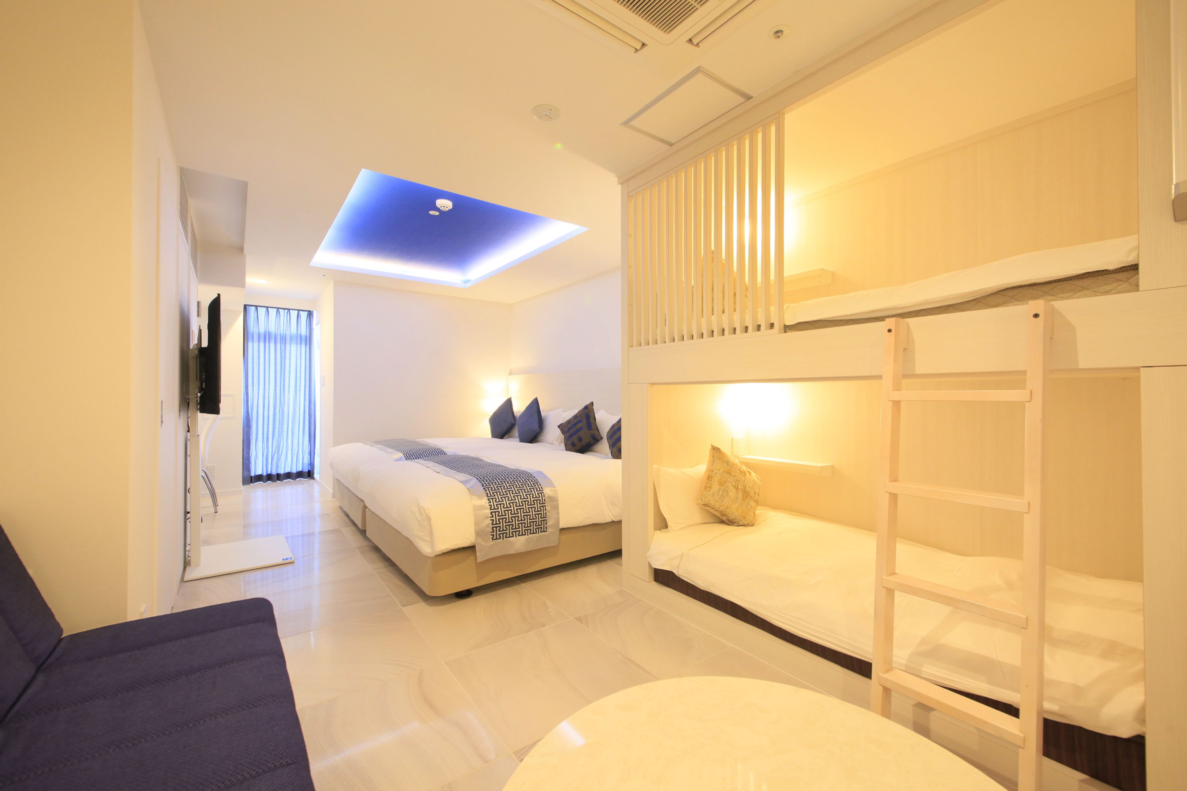 Una habitación de hotel moderna con una cama, un sofá, un escritorio y una lámpara de techo.