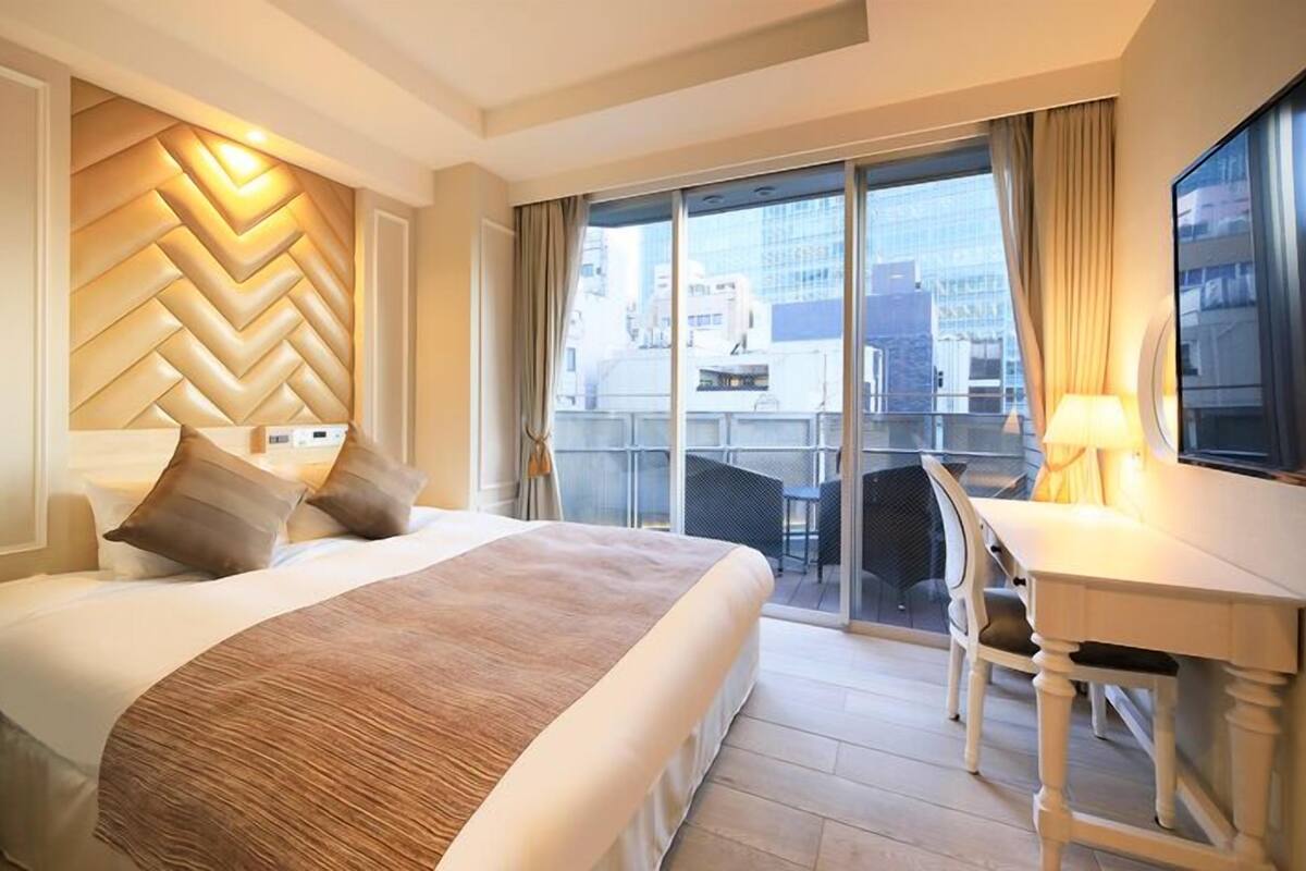 Une chambre d’hôtel avec un grand lit, un bureau et un balcon offrant une vue sur la ville.