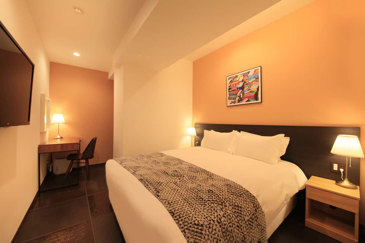 Une chambre d’hôtel avec un lit, un bureau, une chaise et une œuvre d’art au mur.