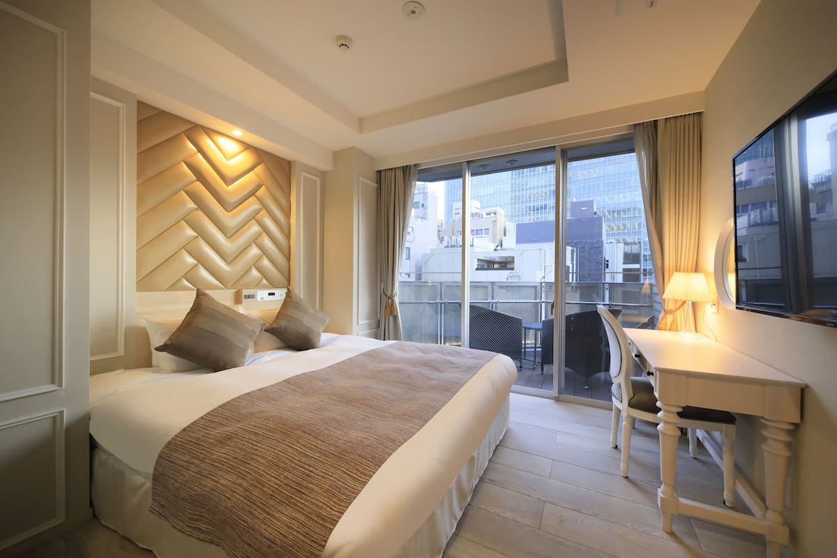 Une chambre d’hôtel avec un grand lit, un bureau et une vue sur la ville par la fenêtre.