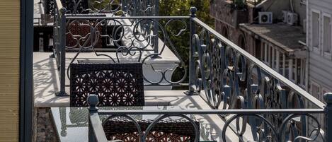 A balcony with a view of the sea, metal railings, and a boat in the distance.