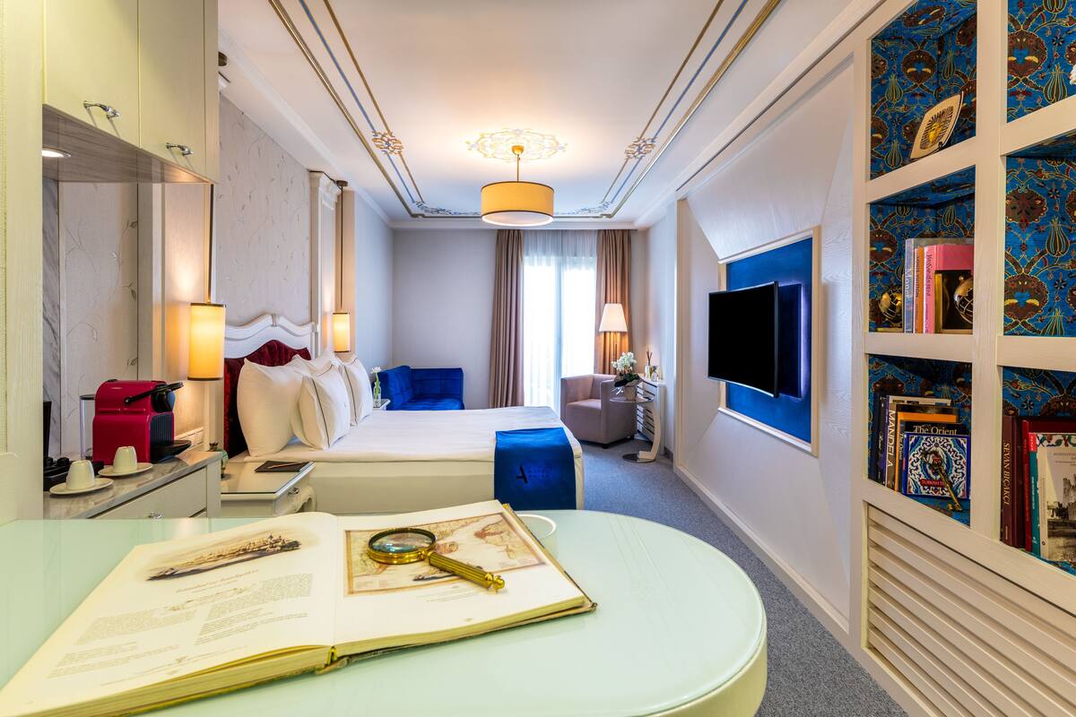 Une chambre d’hôtel avec un lit, un bureau, une bibliothèque et un téléviseur.