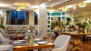 A dining area with multiple tables set for guests, featuring modern chairs and a central decorative piece. - Hotel Amira Istanbul (Istanbul)
