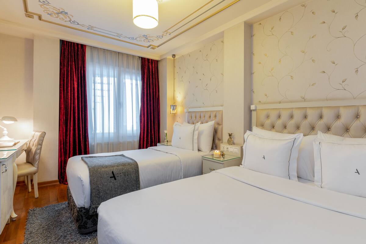 Une chambre d’hôtel avec deux lits, un bureau et une chaise.