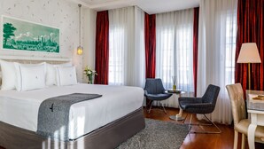 A hotel room with a large bed, two chairs, a small table, and a lamp. - Hotel Amira Istanbul (Istanbul)