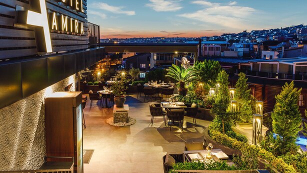A hotel with outdoor dining areas, a view of the cityscape, and a sign indicating the hotel's name. - Hotel Amira Istanbul (Istanbul)