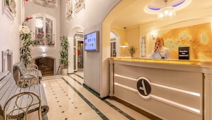 A hotel reception area with a reception desk, a digital screen, and a staircase leading to another floor. - Hotel Amira Istanbul (Istanbul)