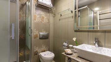 Un baño con ducha, inodoro, lavamanos y perchero para toallas.