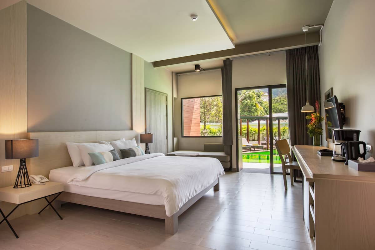 Une chambre d’hôtel moderne avec un grand lit, un bureau et une vue sur une piscine.