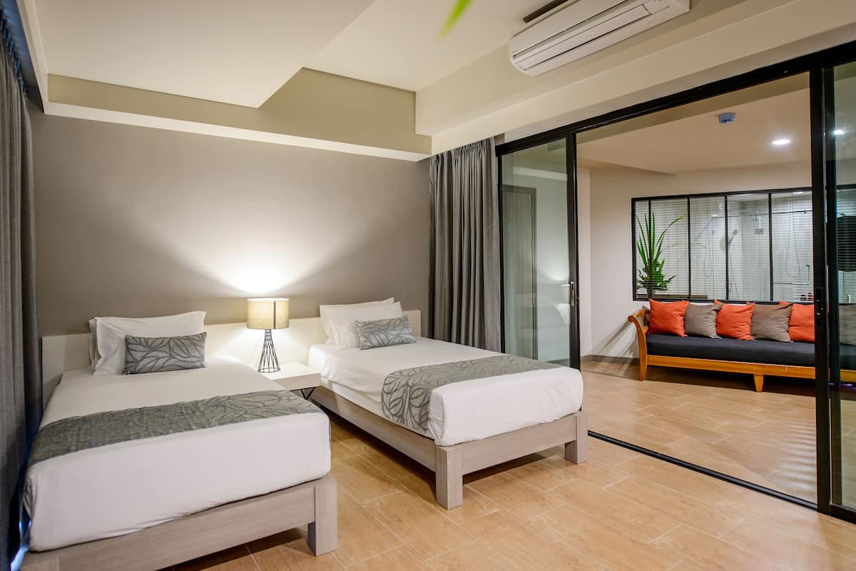 Une chambre d’hôtel avec deux lits, un canapé, une lampe et une grande fenêtre.