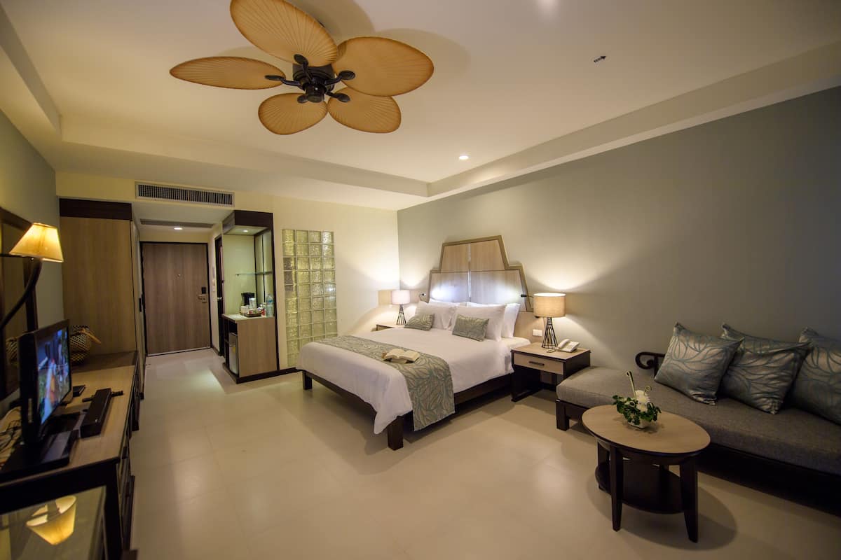 Une chambre d’hôtel moderne avec un grand lit, un canapé, une petite table et un téléviseur.