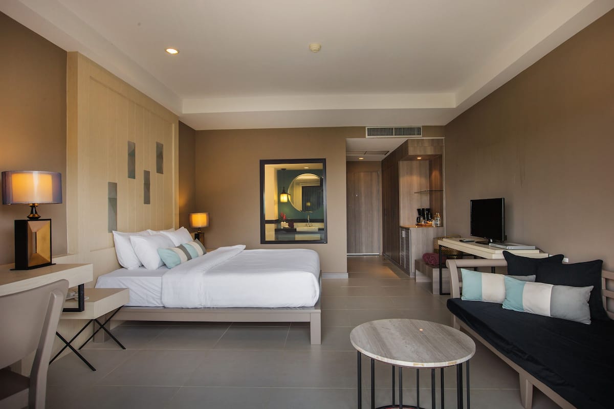 Une chambre d’hôtel moderne équipée d’un lit, d’un bureau, d’un canapé, d’une table ronde et d’un téléviseur.