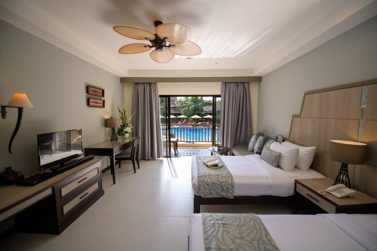 Une chambre d’hôtel avec un lit, un bureau, une télévision et une vue sur une piscine.