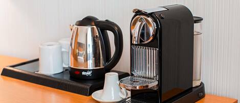 A coffee maker and a kettle on a tray.