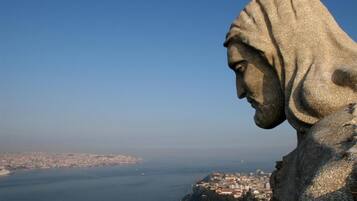 Una gran estatua de piedra con vistas a una ciudad costera.