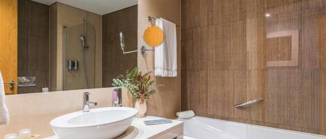 A modern bathroom with a large oval sink, a bathtub, and a shower area.